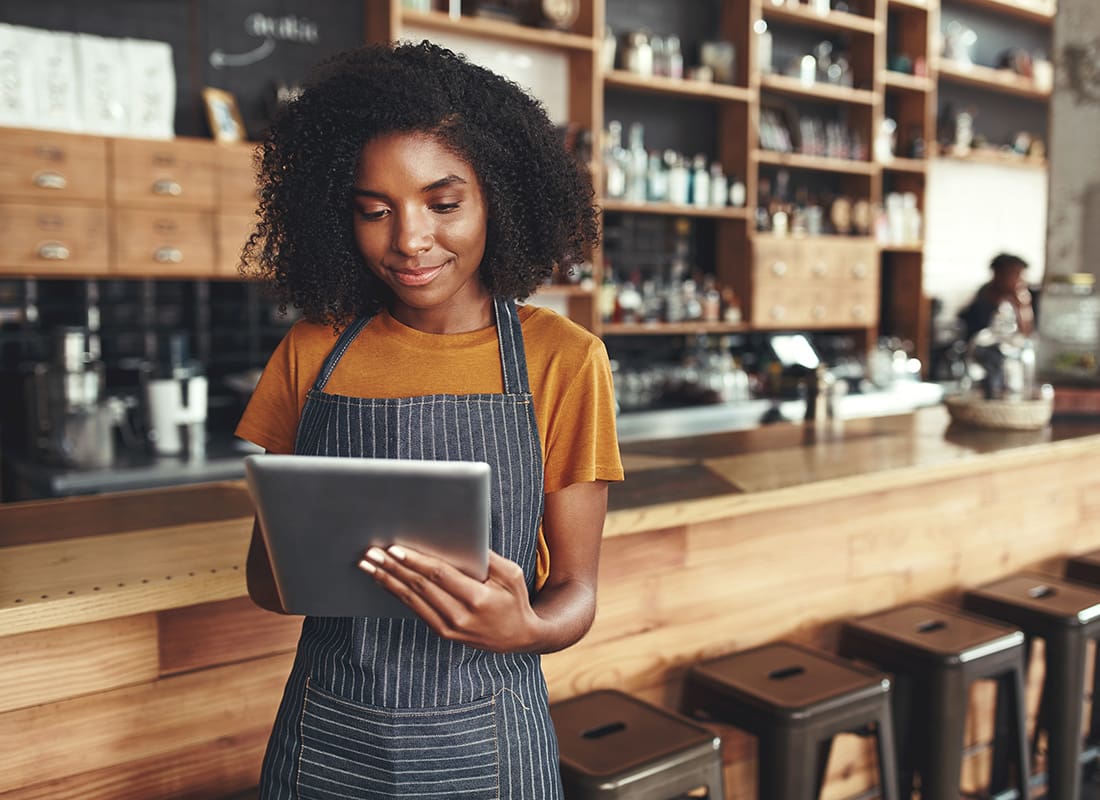 Business Insurance - Portrait of a Young Small Business Owner Holding a Tablet While Standing in her Cafe