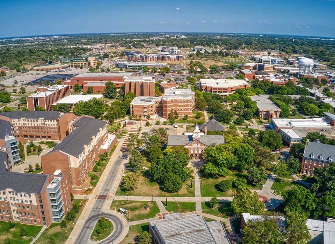 Contact - Aerial View of the Wichita University Campus Buildings Surrounded by Green Foliage on a Sunny Day