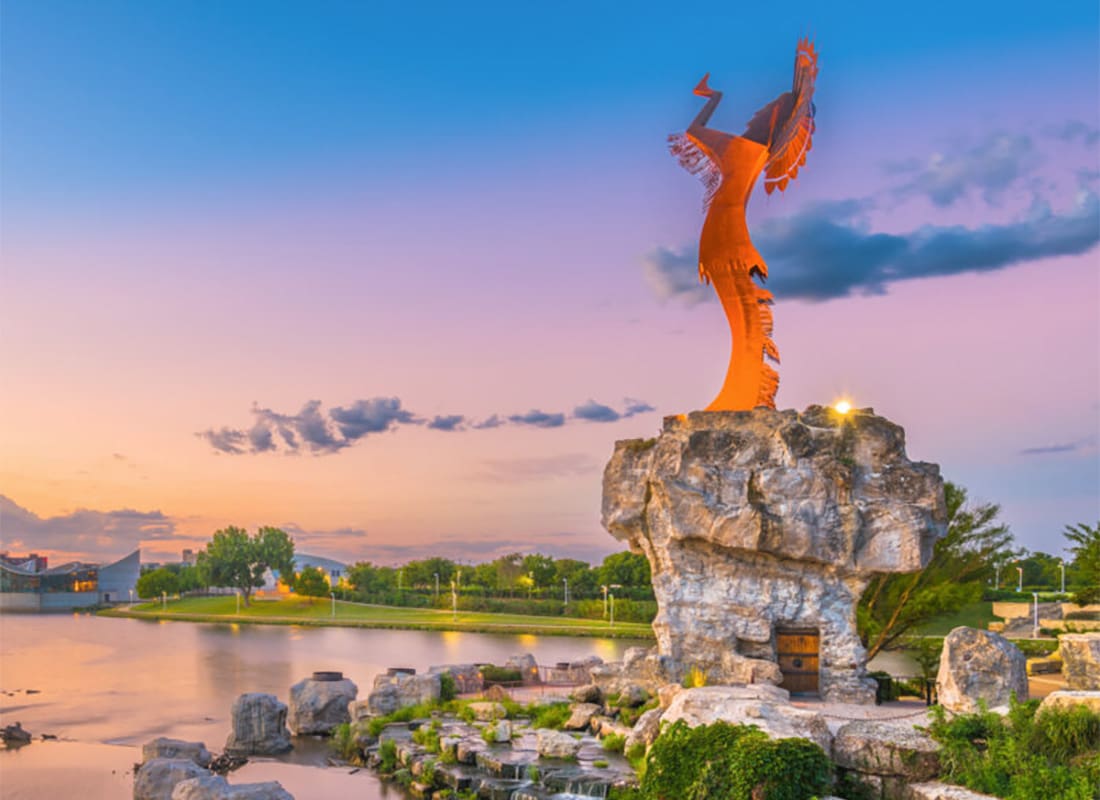 Review Us - Keeper of the Plains Statue in Wichita Kansas on Top of Rocks at Sunset